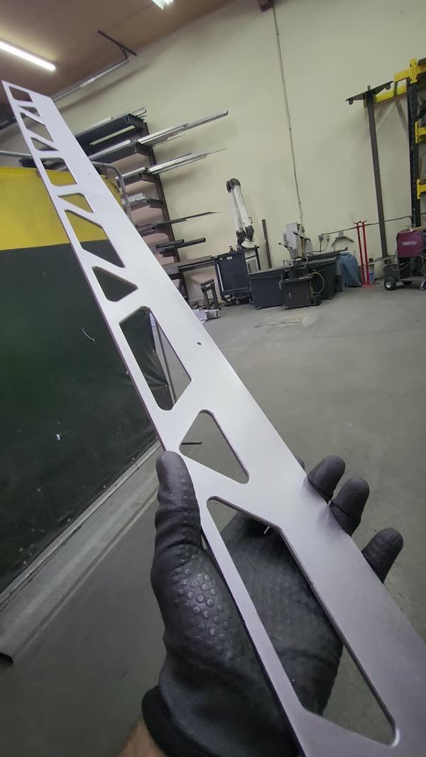 Laser-cut aluminum part held up in the shop